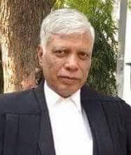 Senior man with white hair wearing a black legal robe and white collared shirt.